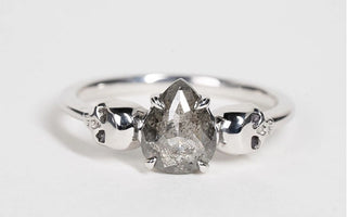 Salt and pepper diamond alternative engagement ring with skulls on white gold band