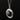 A silver oval pendant necklace featuring a smooth, polished black onyx centre stone, surrounded by an ornate leafy wreath border, suspended from a matching link chain against a solid black background.