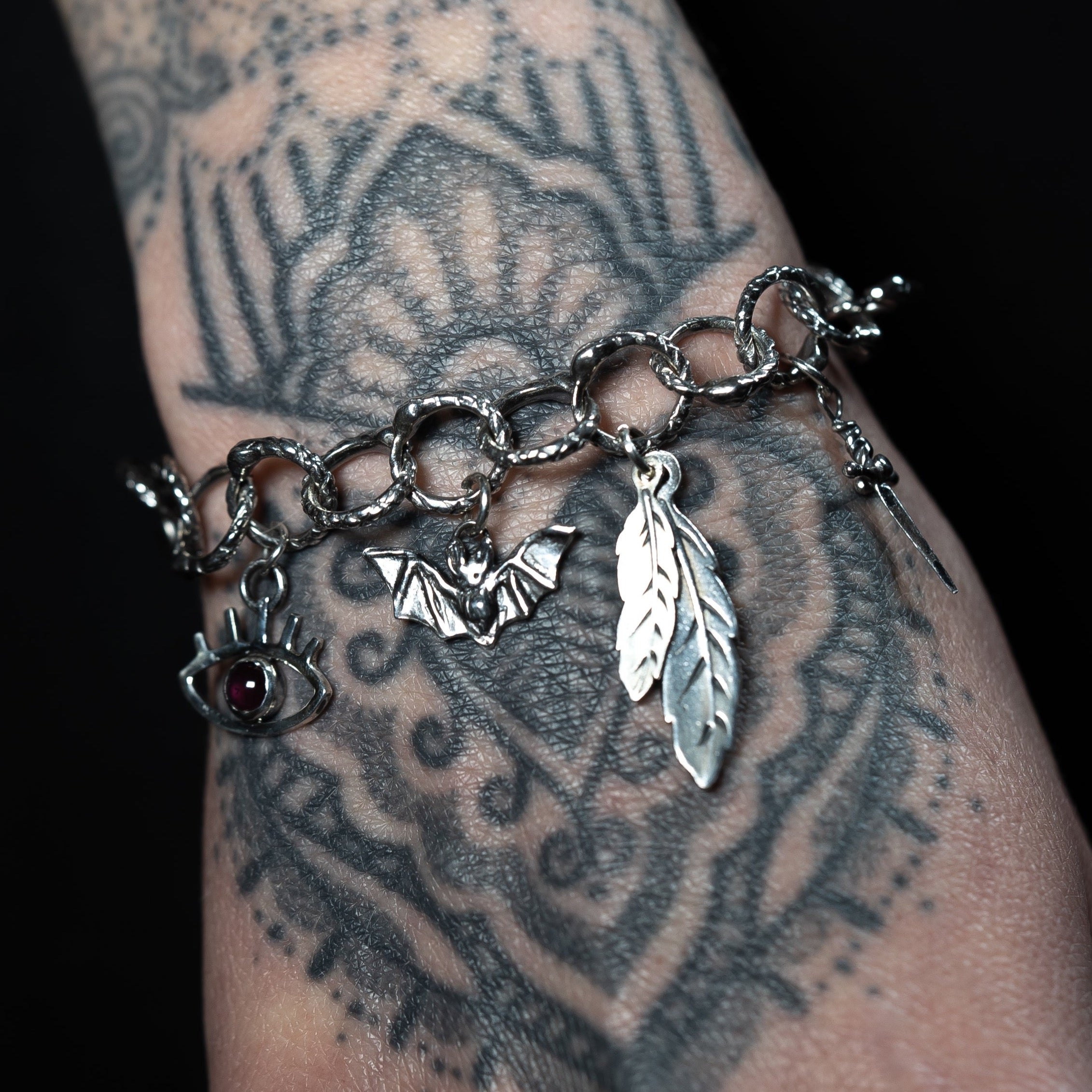 Handmade gothic charm bracelet on a tattooed female wrist