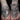 two tattooed hands wearing different Bonearrow snake link bracelets and a snake link charm bracelet for men and women on a black backdrop