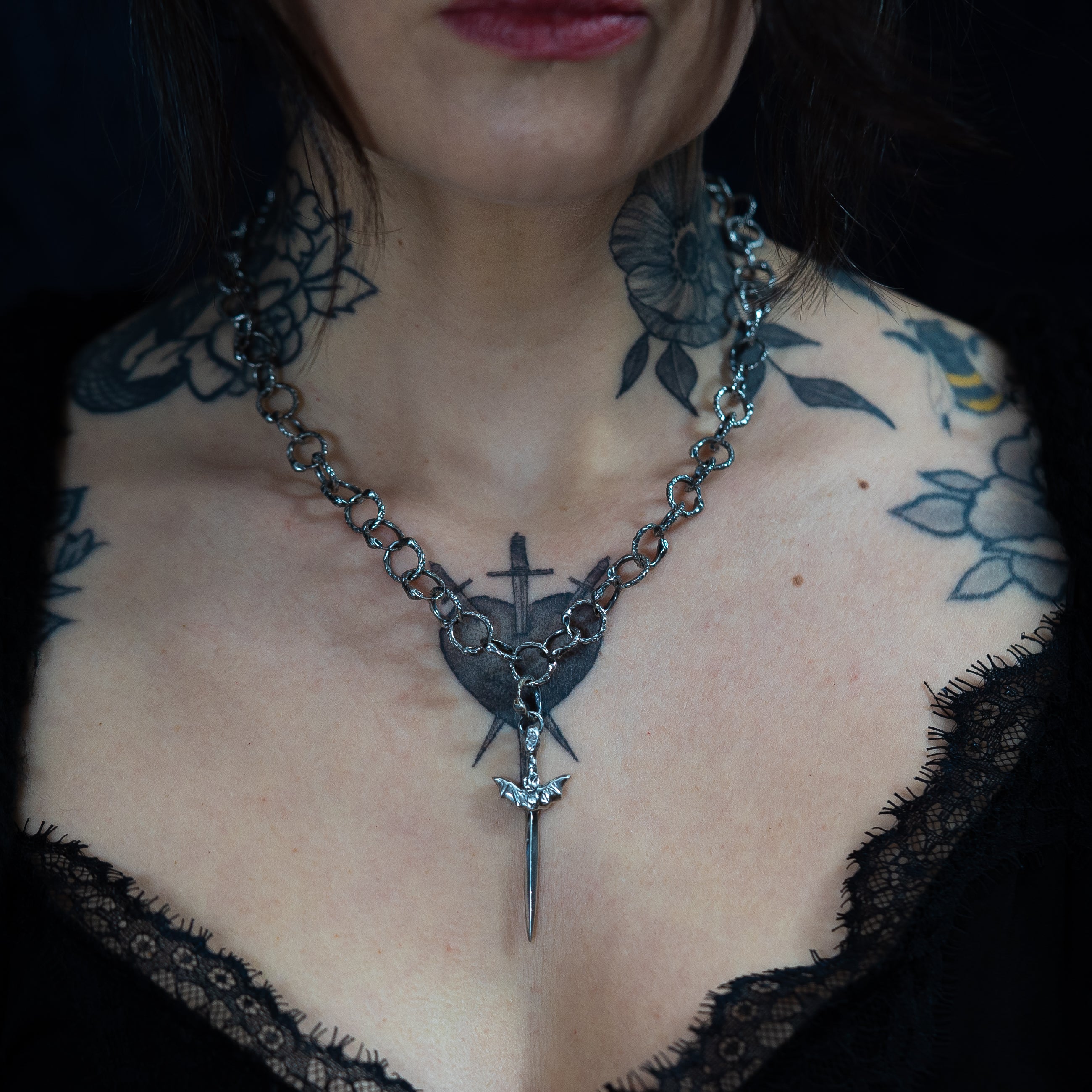 Alternative model with neck tattoos wearing snake chain link necklace with dagger pendant