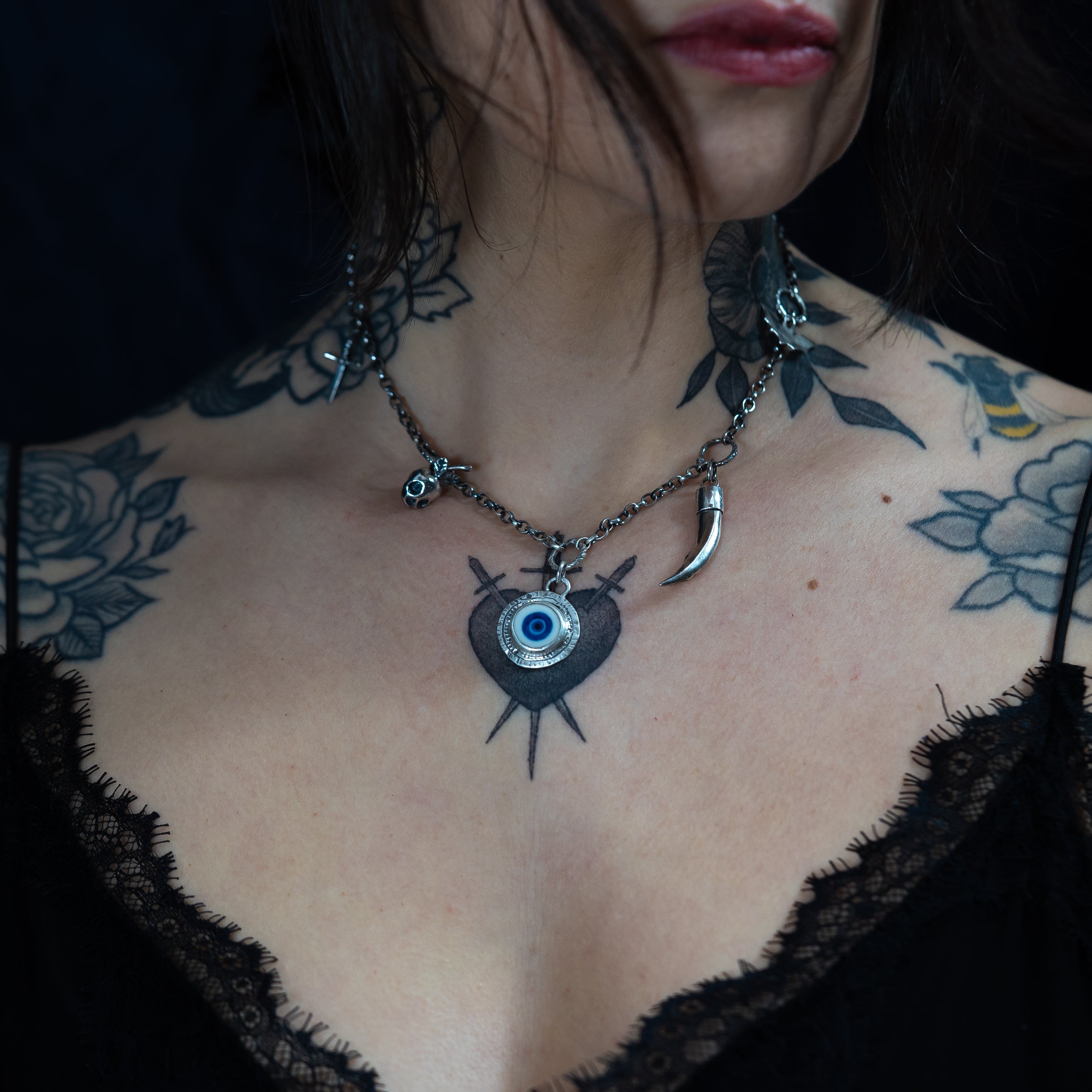 gothic charm necklace in silver, made by hand in the UK, worn by a tattooed model on a black background