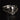 White gold engagement ring with a large salt and pepper diamond, with a black diamond shaped wedding band on a black background