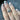 Hand with decorative nail art and a handmade silver ring with an all-seeing eye design and a central round moonstone, on a dark surface
