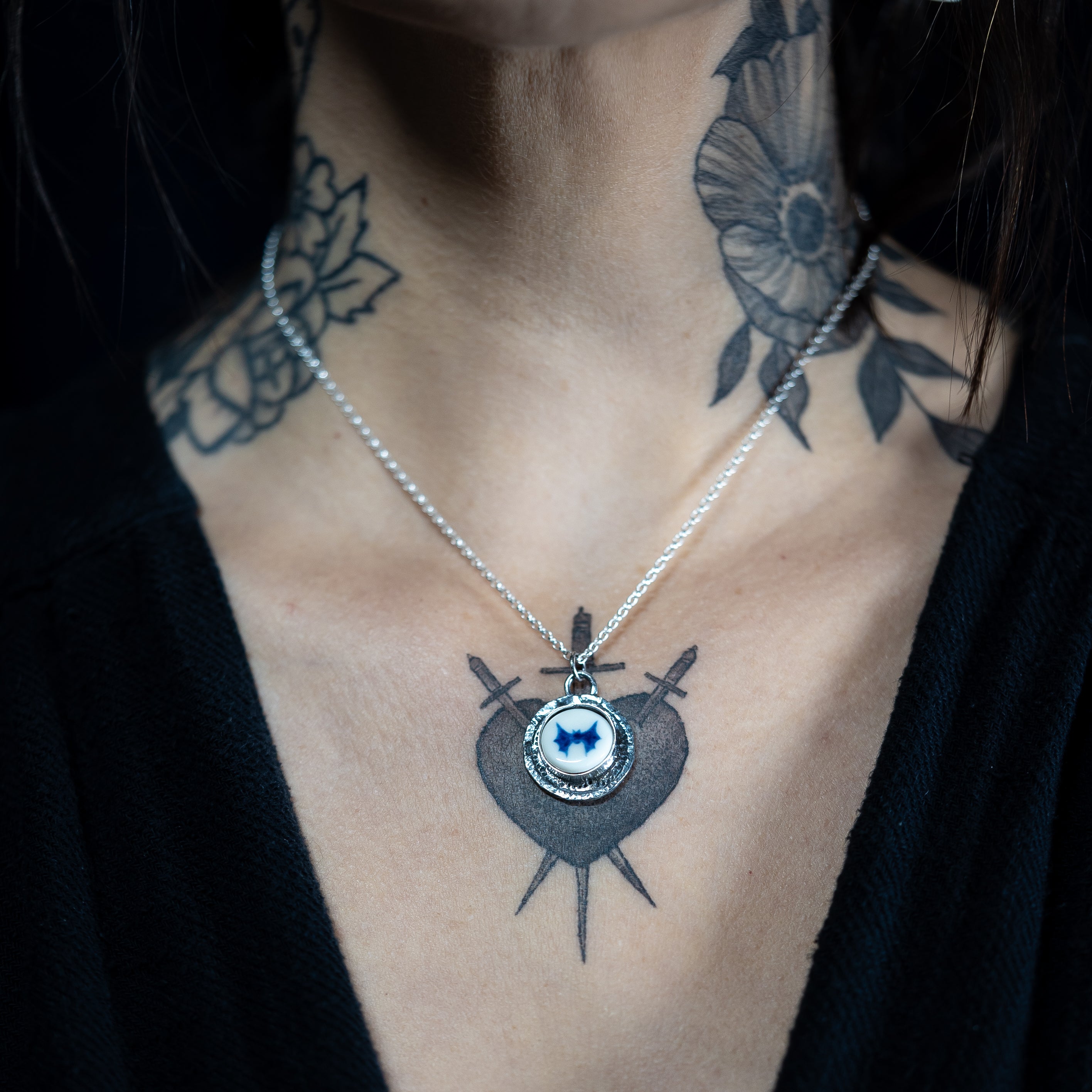 Alternative model with neck tattoos wearing a bat pendant