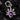 A sterling silver pendant featuring a teardrop-shaped amethyst gemstone with two skulls on either side and a crown above the stone, set against a black textured background.