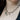A close-up of a person's neck wearing a sterling silver charm necklace with multiple small pendants, including a dagger, a storm cloud, a bat, and a planchette pendant.