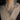 Close-up of a delicate necklace with a moonstone pendant on a person's neck with tattoos.