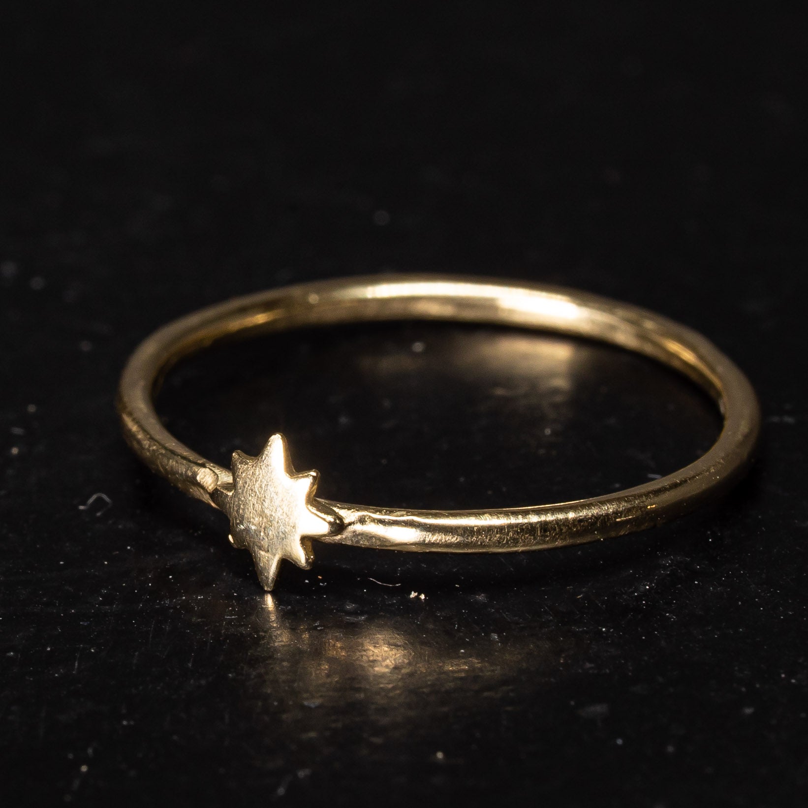 Side view of gold eight point star ring