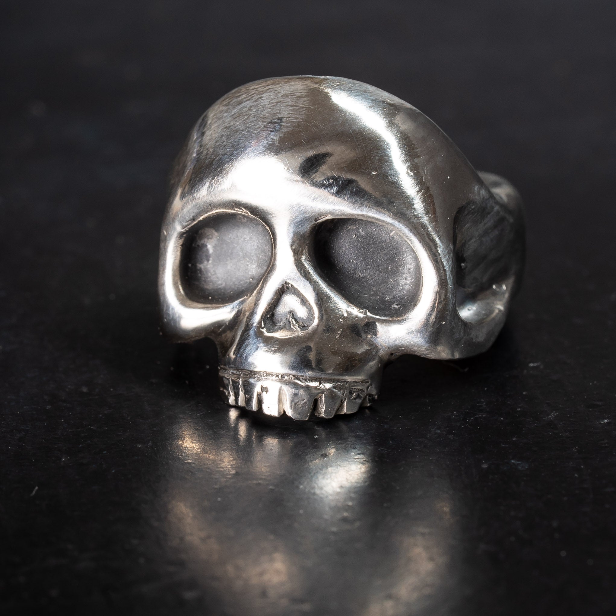Sterling silver skull ring with no bottom jaw on black background